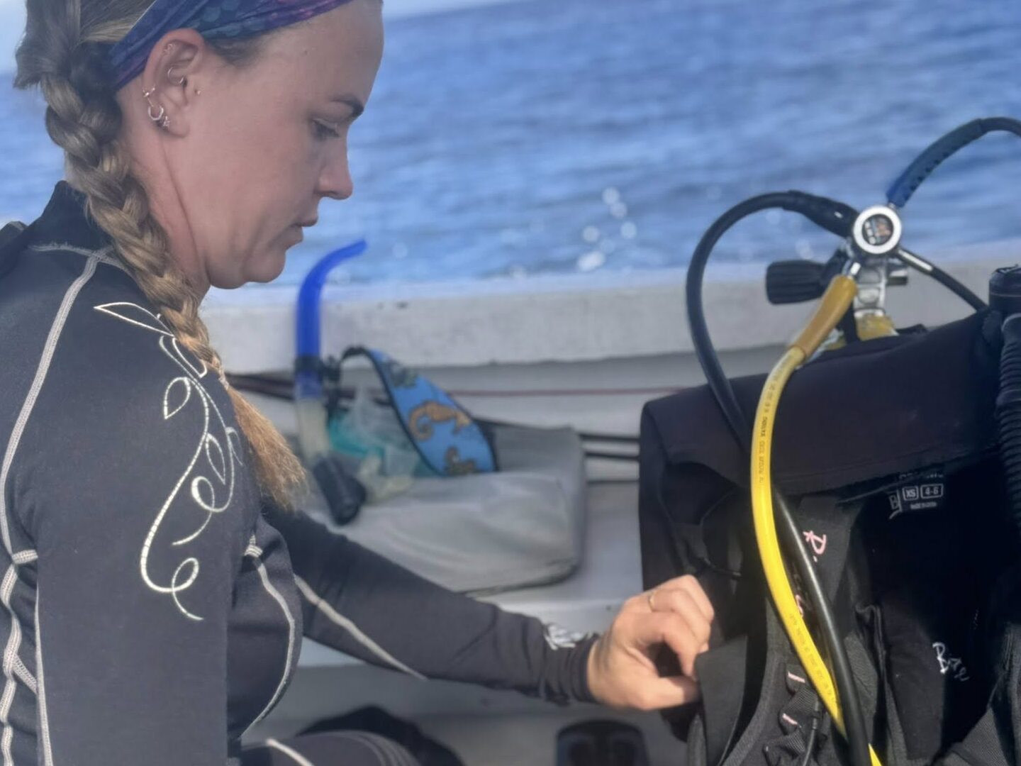Diver kneeling on a boat managing scuba equipment and practicing skills to ease dive anxiety and build confidence