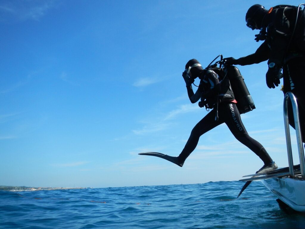 two scuba diving buddies jumping into the water together for a safe dive