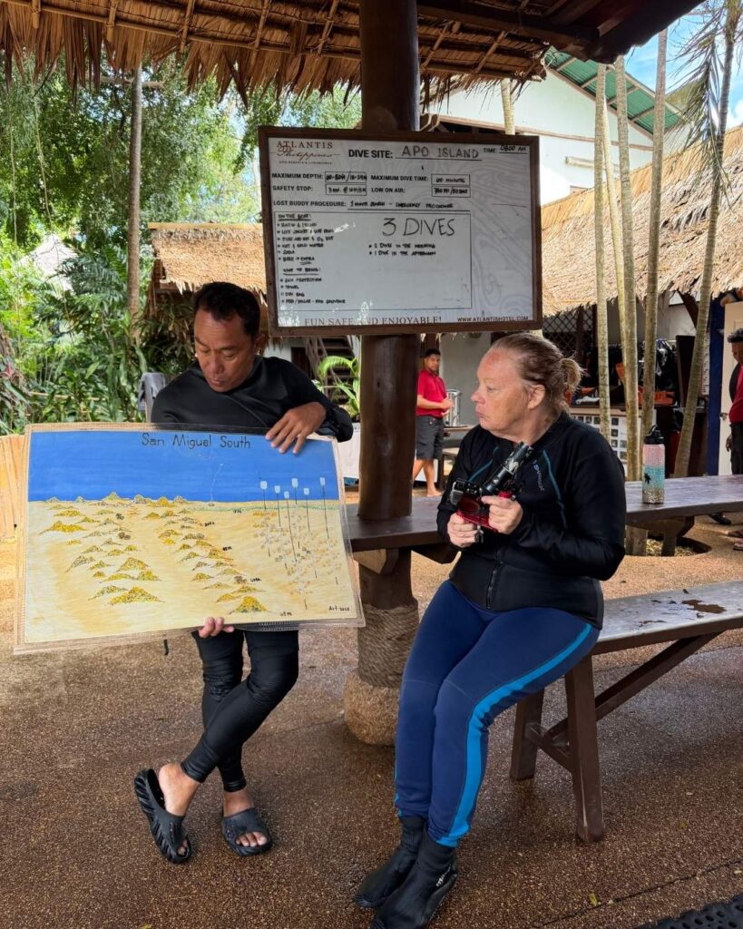 cuba divers preparing gear on a beach in the Philippines, with a guide coordinating logistics during travel to the Philippines for a dive trip