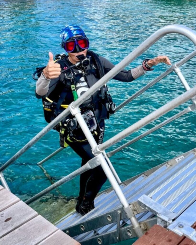 Woman over 50 entering the water using dock stairs for scuba diving in Bonaire
