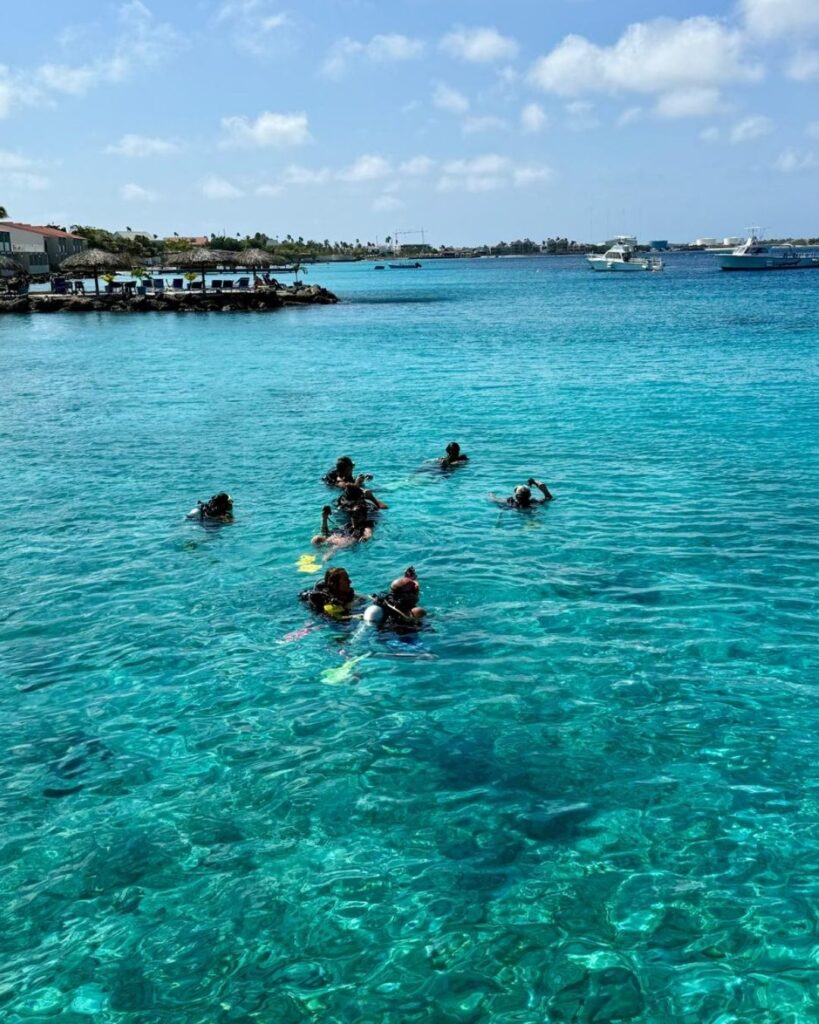 Scuba divers entering clear shallow water from shore in Bonaire