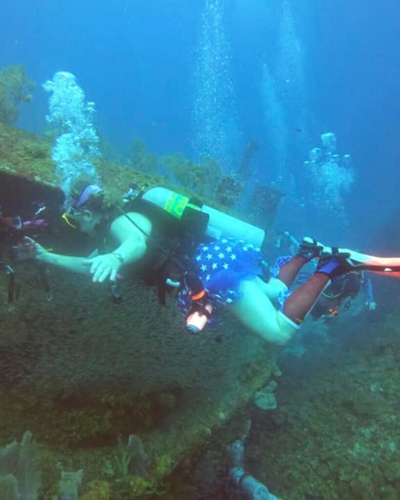 Female scuba diver exploring reef wall in Roatán with clear visibility because of successful Roatan dive trip planning