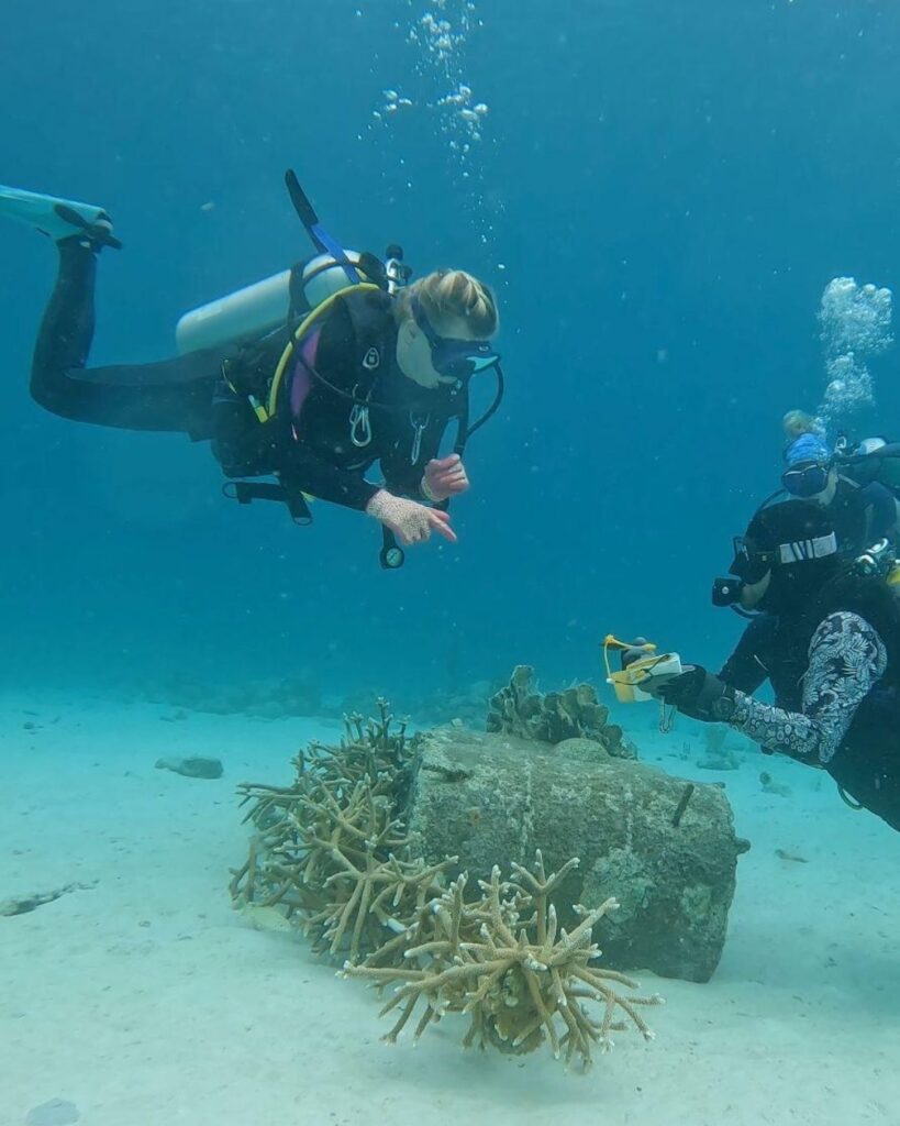 Women scuba diving with a guide in clear water in Bonaire