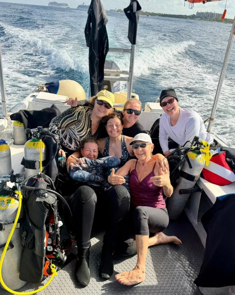 group of older women scuba divers laughing together on a dive boat building confidence and connection