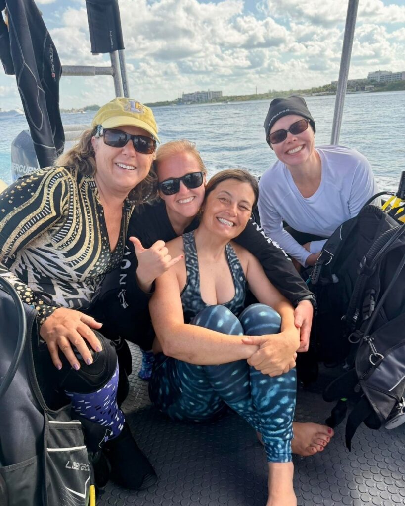 Group of women scuba divers smiling on a boat during a Philippines dive adventure with Rise and Dive