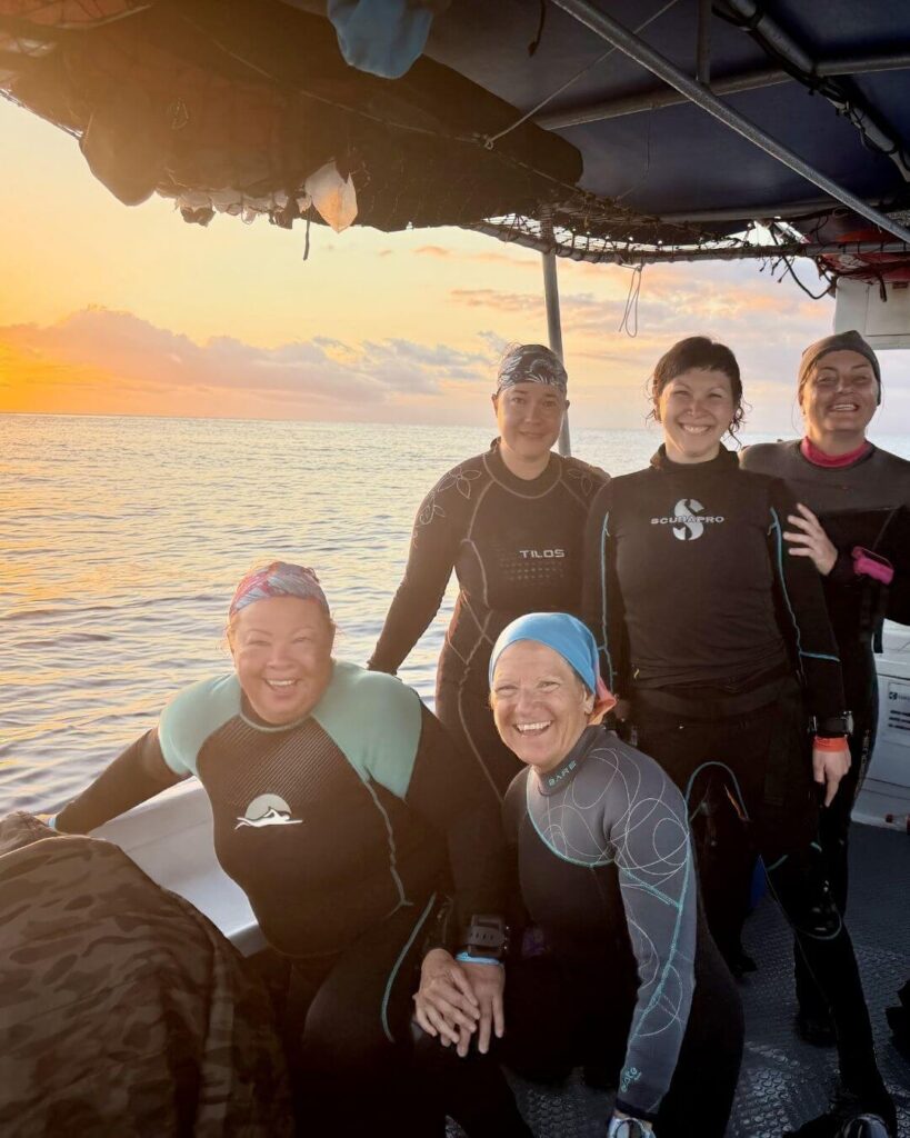 Group of women scuba divers smiling on a boat after a drift dive in Cozumel
