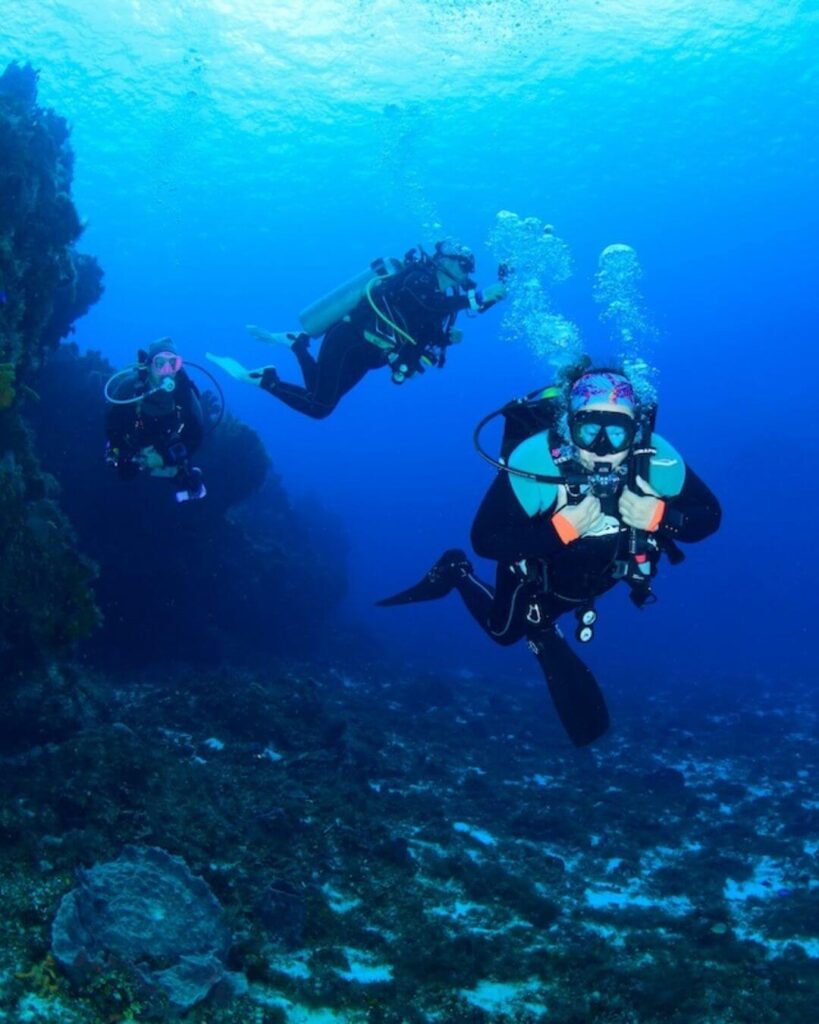 Three women scuba divers practicing buoyancy control skills while drift diving in Cozumel current