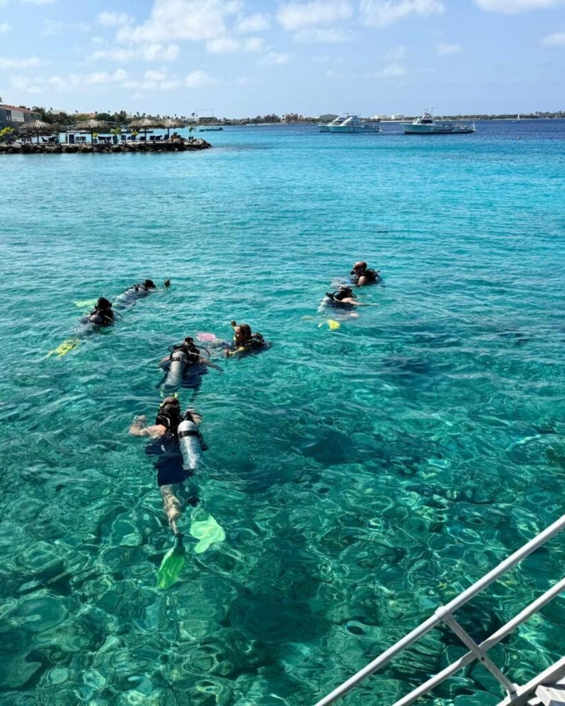 Divers entering water from dock for house reef shore diving in Bonaire