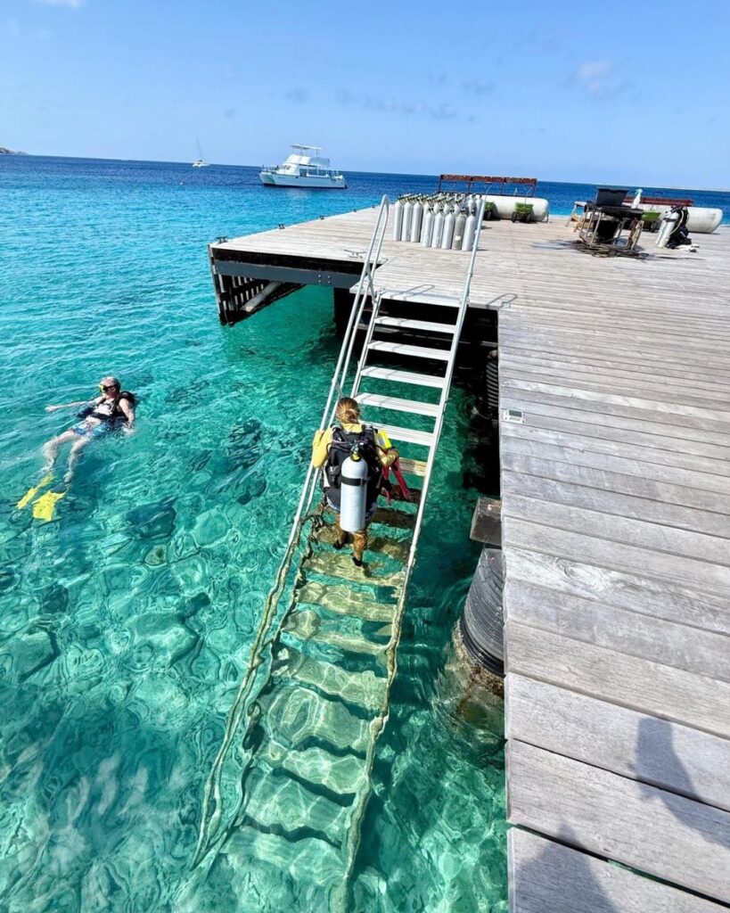 Scuba divers exploring Calabas Reef house reef in Bonaire with clear water
