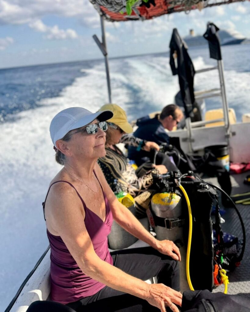 Woman sitting quietly on a dive boat before a scuba dive, reflecting somatic practice, nervous system awareness, and intentional diving preparation.